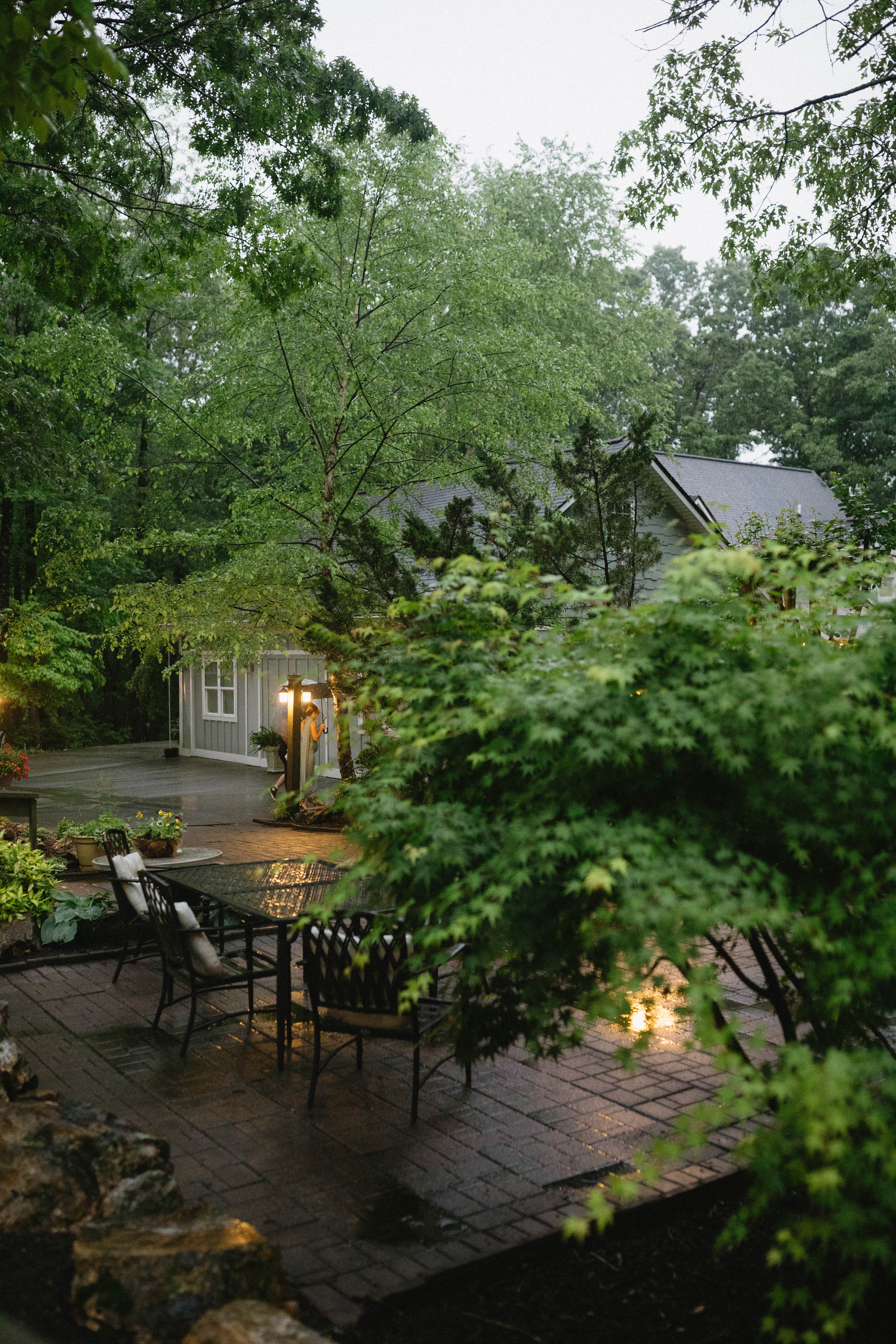 A patio surrounded by greenery on a rainy day.