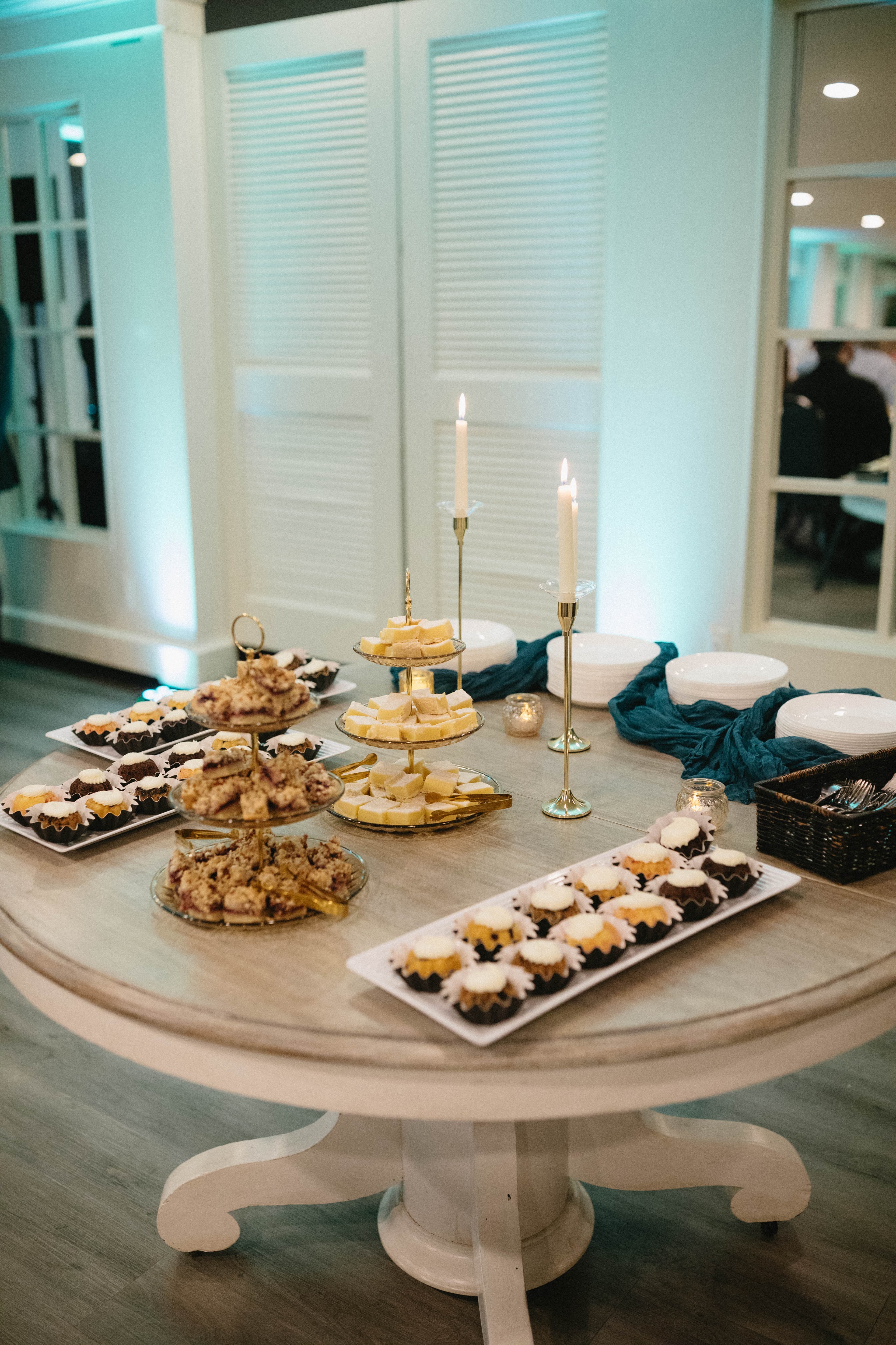 A decorative dessert table featuring various sweets, including cupcakes and layered treats, with candles and plates.