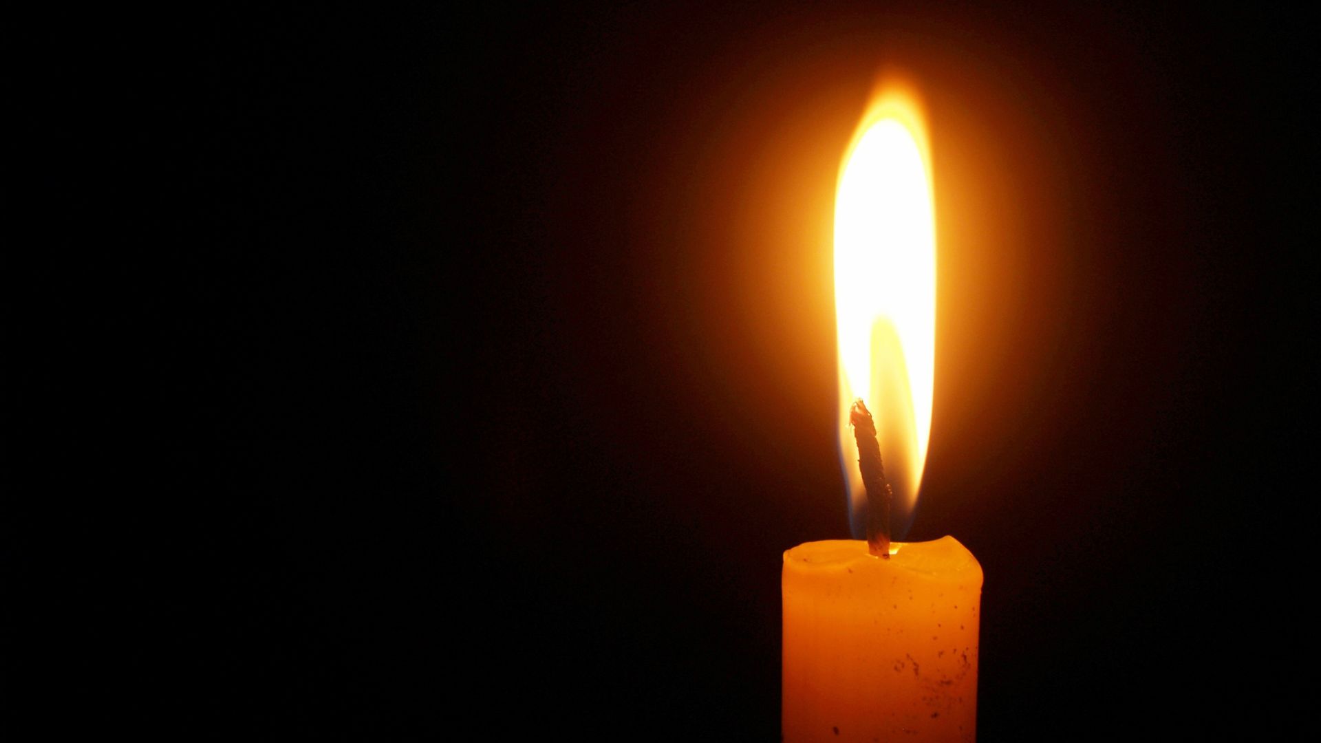 Single lighted candle with black background