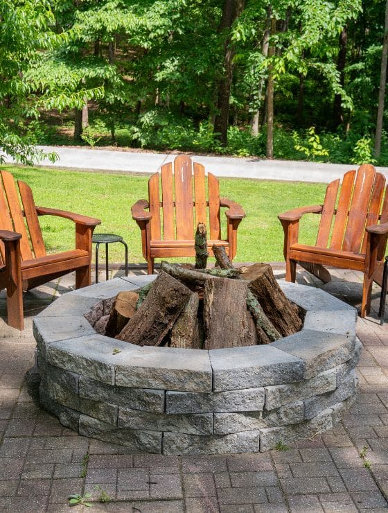 Three wood Adirondack chairs around a stone fireplace