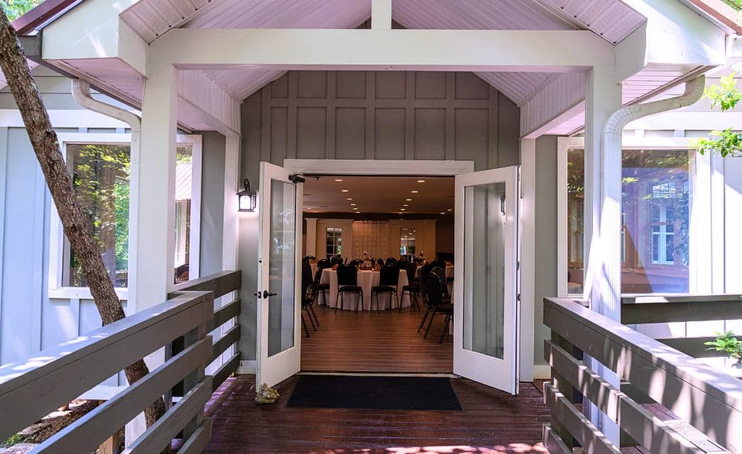 Deck and open doorway looking into an event room full of tables set up for an event