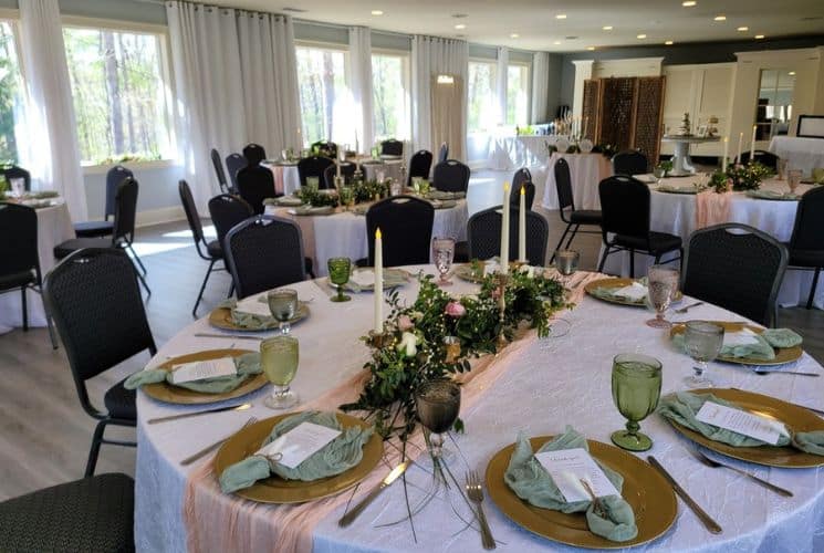 Event center with large windows and several round tables in white tablecloths and decorated for a wedding