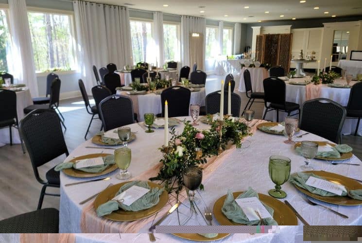 Event center with large windows and several round tables in white tablecloths and decorated for a wedding